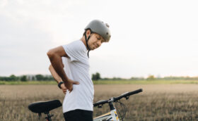 Man showing signs of pain after cycling, related to common spinal injury causes and prevention strategies.