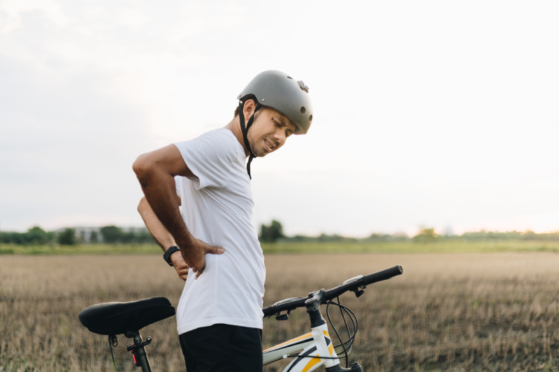 Man showing signs of pain after cycling, related to common spinal injury causes and prevention strategies.